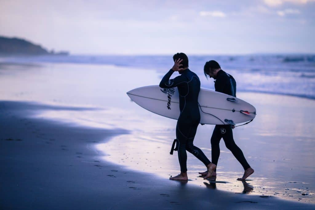 People_in_wetsuits_on_beach_surfboards